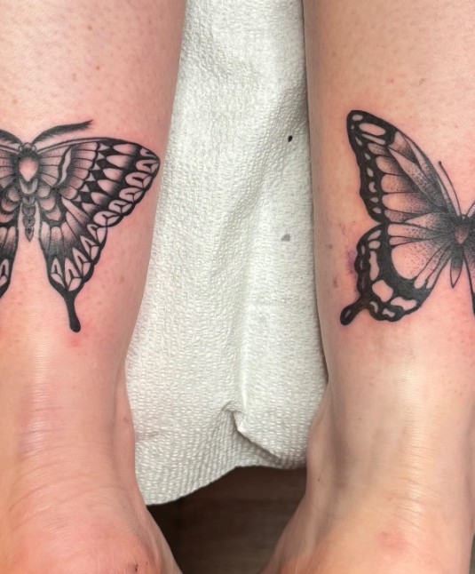 Two black butterfly tattoos on ankles