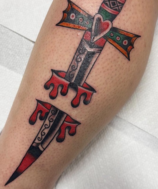 Traditional dagger and heart tattoo on a forearm